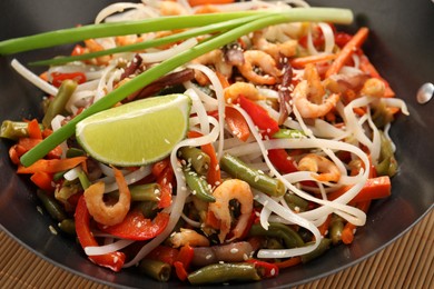 Photo of Shrimp stir fry with noodles and vegetables in wok on table, closeup