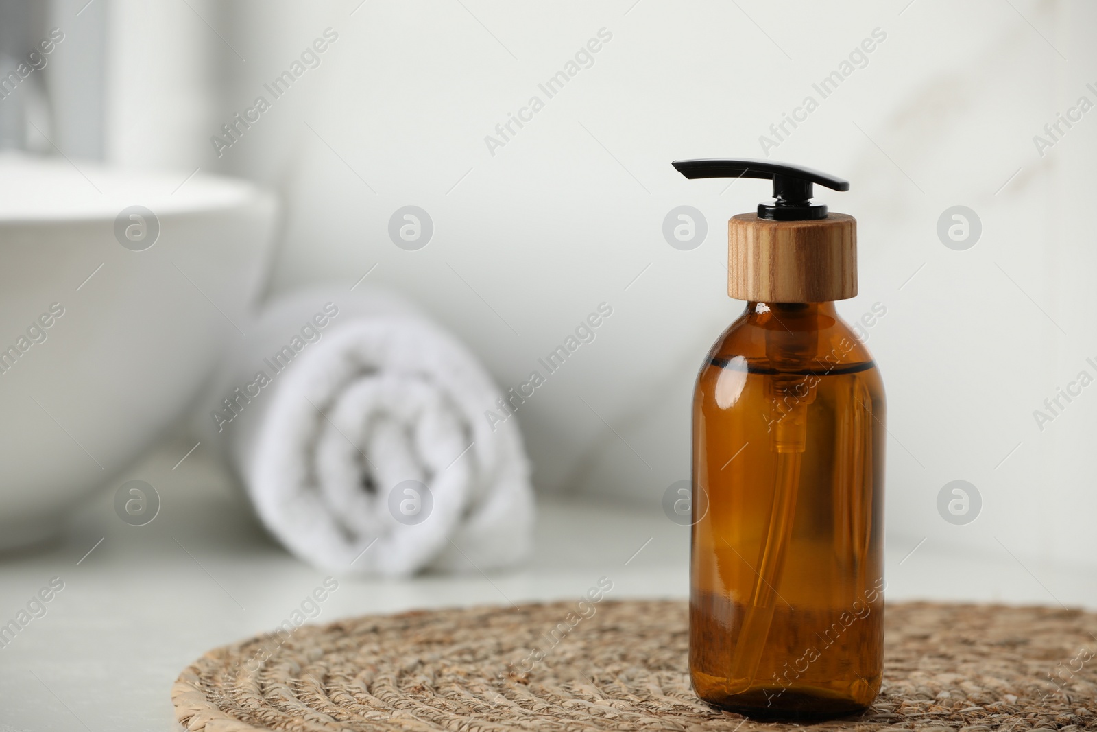 Photo of Bottle with dispenser cap on table in bathroom, closeup. Space for text