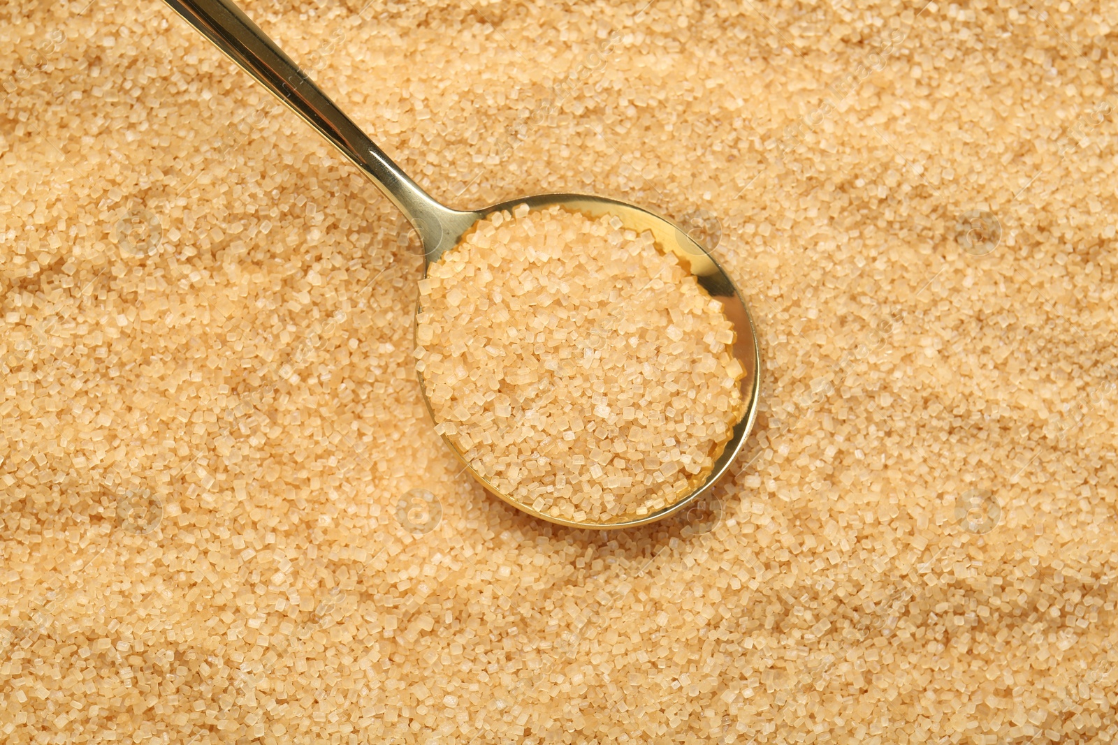 Photo of Spoon on granulated brown sugar, top view