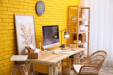 Photo of Stylish home office interior with comfortable workplace near yellow brick wall