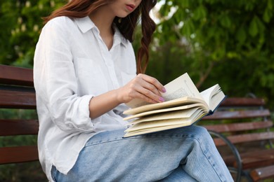 Photo of Young woman reading on bench in park, closeup