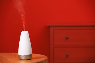 Modern essential oil diffuser on table indoors. Space for text