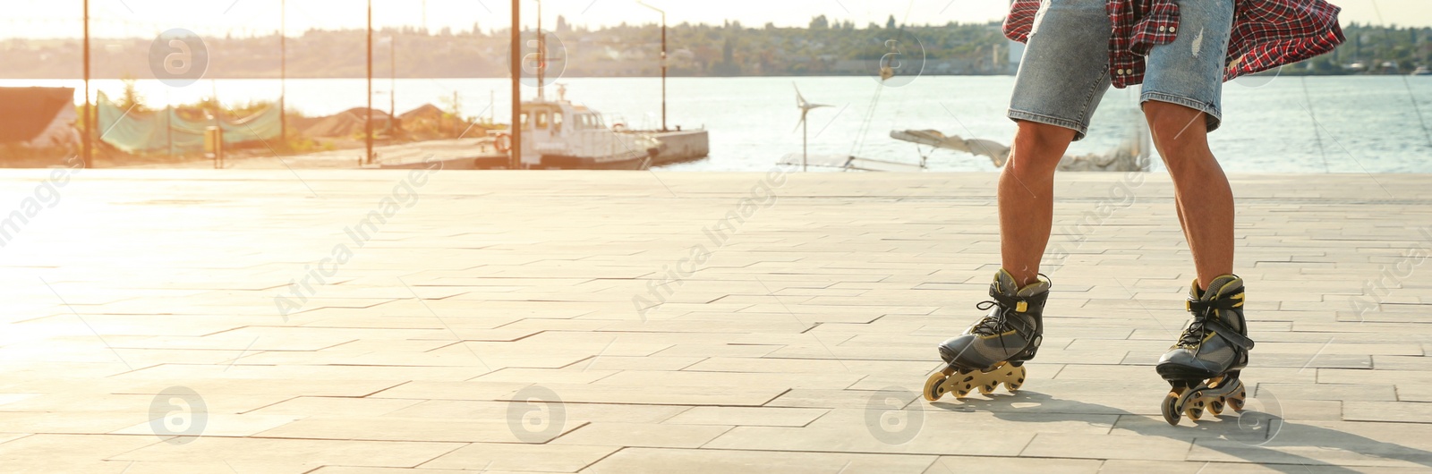 Image of Young man roller skating on pier near river, space for text. Banner design