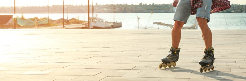 Image of Young man roller skating on pier near river, space for text. Banner design