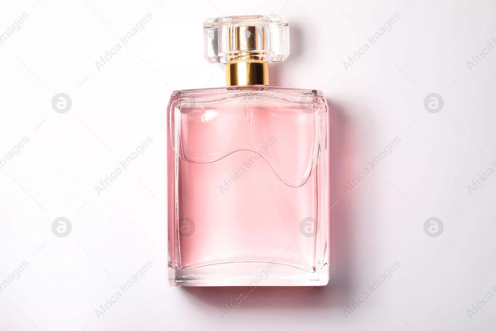 Photo of Pink women's perfume in bottle on white background, top view