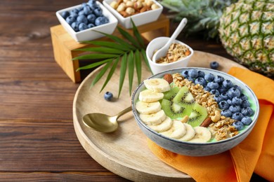 Photo of Tasty smoothie bowl with fresh fruits and oatmeal served on wooden table, space for text