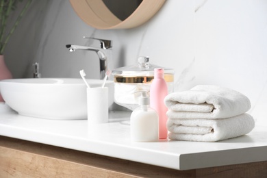 Photo of Folded towels and toiletries on countertop in bathroom