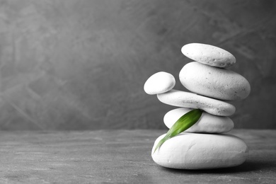 Photo of Stack of zen stones and bamboo leaf on table against grey background. Space for text