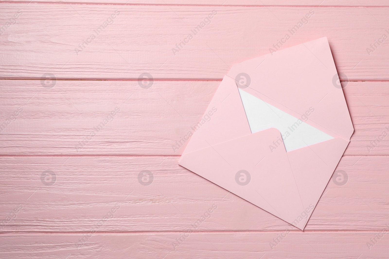 Photo of Letter envelope with card on pink wooden table, top view. Space for text