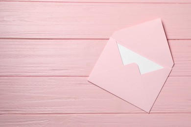 Letter envelope with card on pink wooden table, top view. Space for text