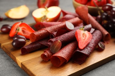 Photo of Delicious fruit leather rolls on grey table, closeup