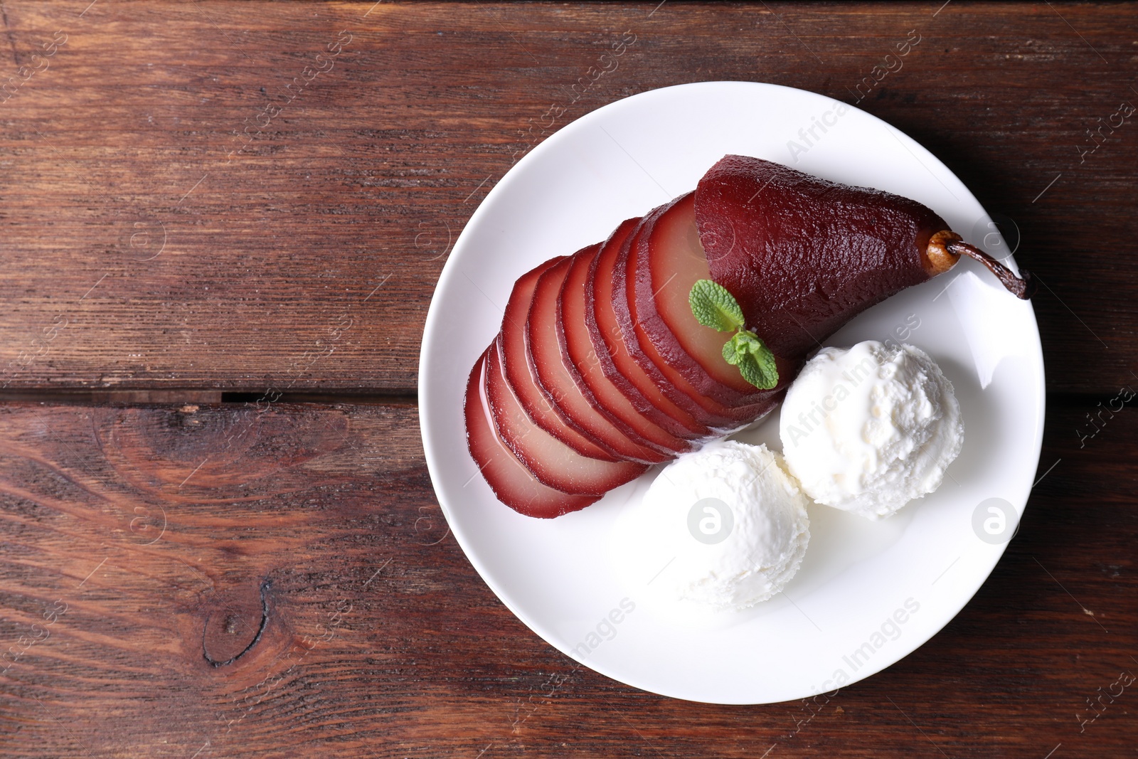 Photo of Tasty red wine poached pear and ice cream on wooden table, top view. Space for text