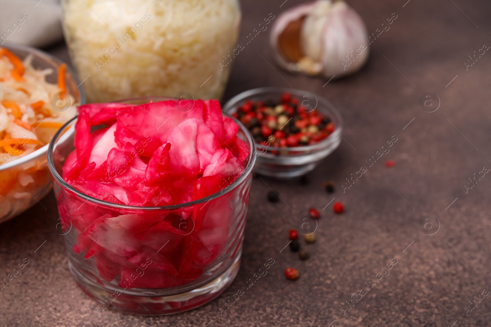 Photo of Delicious sauerkraut prepared according to different recipes on brown table, closeup. Space for text