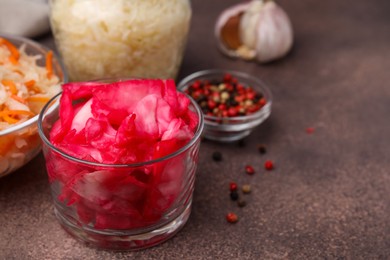 Photo of Delicious sauerkraut prepared according to different recipes on brown table, closeup. Space for text