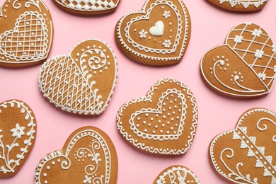 Gingerbread hearts decorated with icing on pink background, flat lay