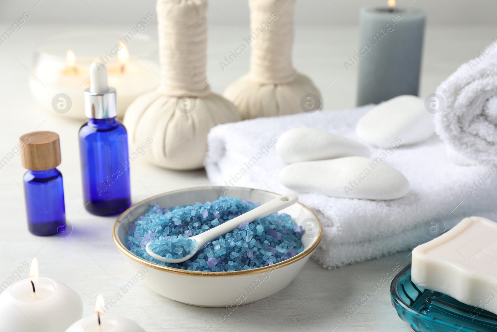 Photo of Spa composition. Cosmetic products, soap, towels, sea salt and burning candles on light table