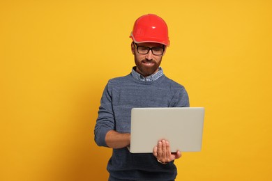 Photo of Professional engineer in hard hat with laptop on yellow background