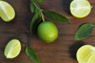 Fresh limes and leaves on wooden table, flat lay