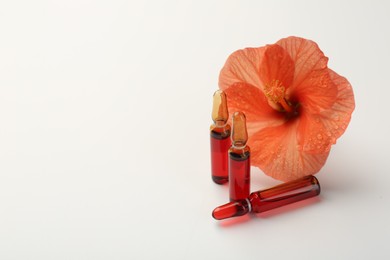 Photo of Skincare ampoules and hibiscus flower on white background. Space for text