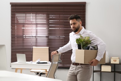 Upset dismissed man carrying box with personal stuff in office