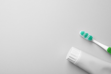 Photo of Blank tube of toothpaste and brush on white background, top view with space for text