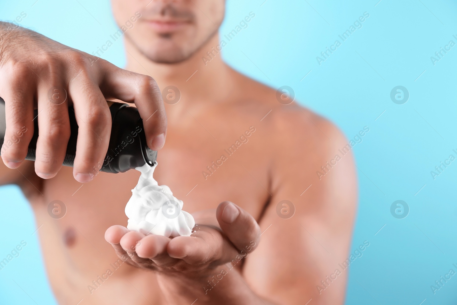 Photo of Young man with shaving foam against color background, closeup