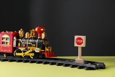 Photo of Road Stop sign as barrier blocking way for toy train on yellow surface, closeup. Development through obstacles overcoming