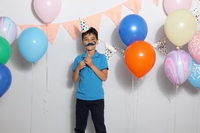 Photo of Happy boy near bright balloons at birthday party indoors