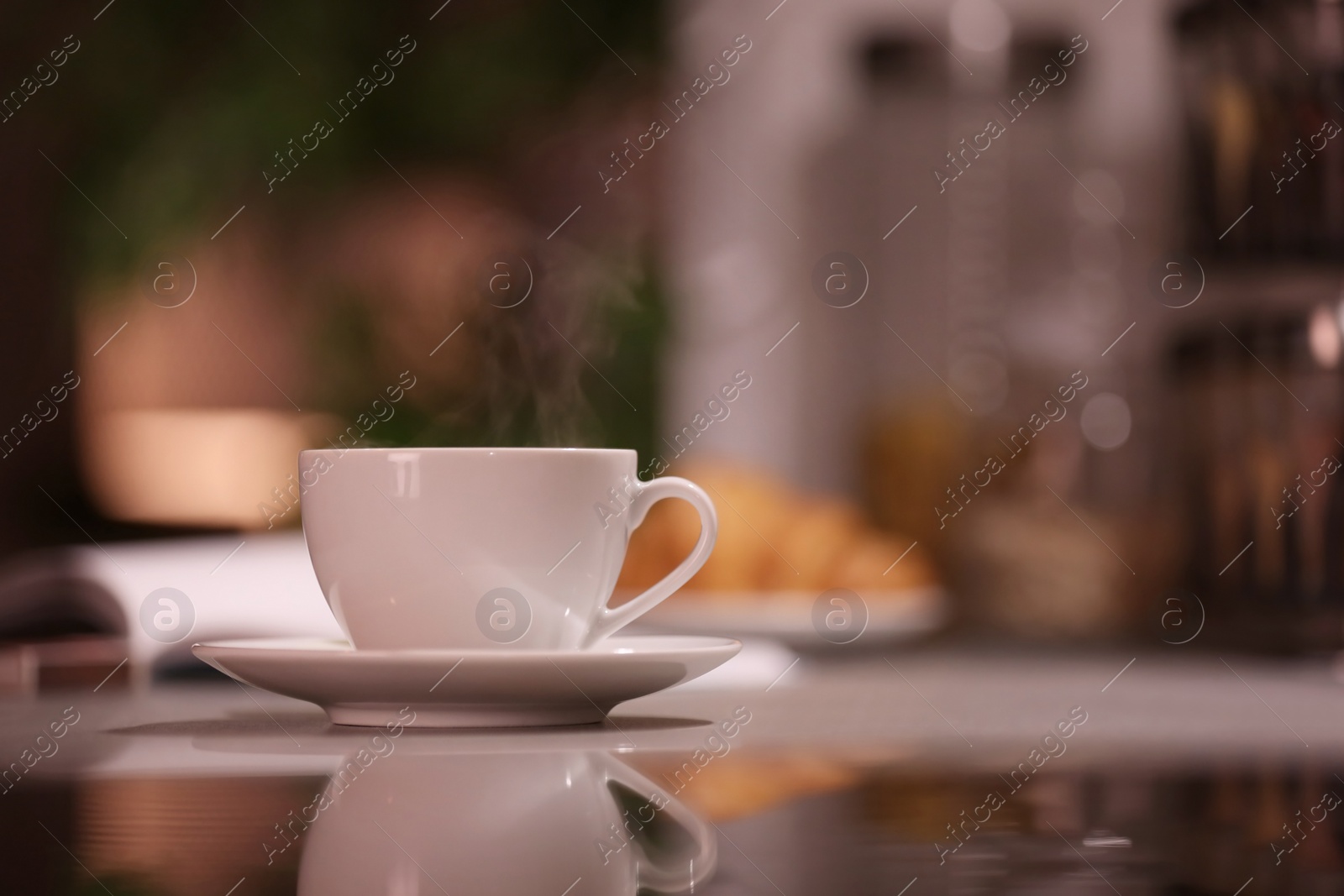 Photo of Cup of hot coffee on blurred background