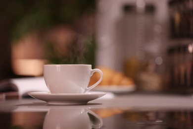 Photo of Cup of hot coffee on blurred background