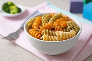 Bowl with tasty fusilli pasta on wooden table, closeup