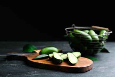 Photo of Fresh seedless avocados with green leaves on table against dark background. Space for text