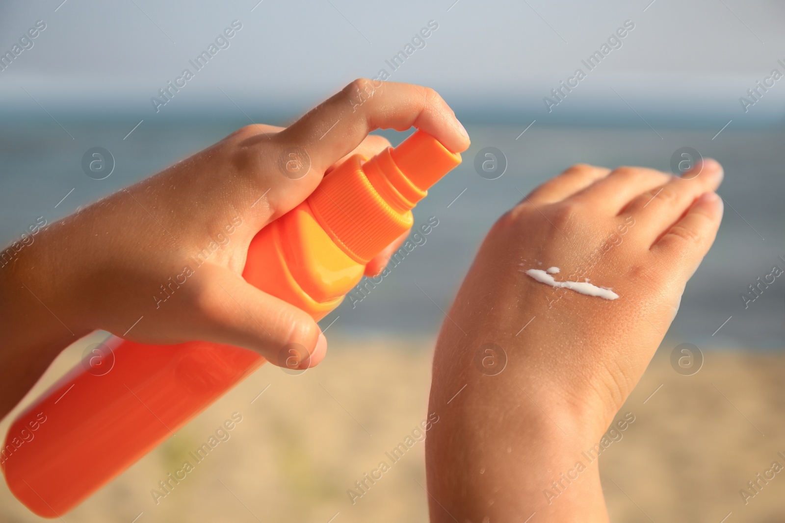 Photo of Child applying sunscreen near sea, closeup. Sun protection care