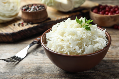 Photo of Tasty fermented cabbage on wooden table, closeup