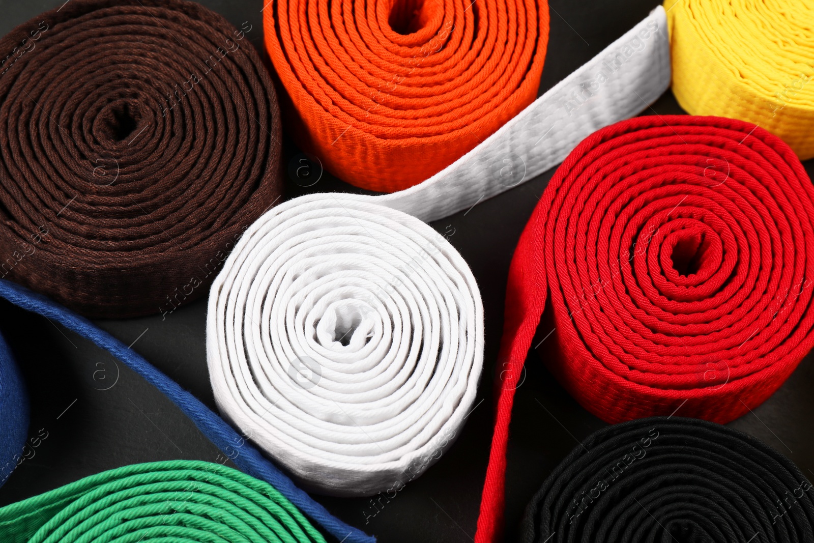 Photo of Colorful karate belts on gray background, closeup