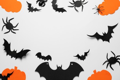 Flat lay composition with paper pumpkins, bats and spiders on white background, space for text. Halloween celebration