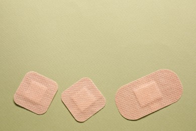 Photo of Different contraceptive patches on green background, flat lay. Space for text