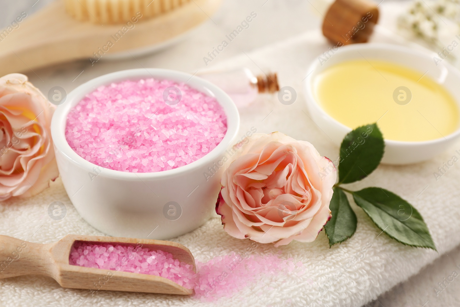 Photo of Pink sea salt and beautiful flowers on towel, closeup
