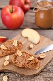 Photo of Fresh apples with peanut butter on wooden table