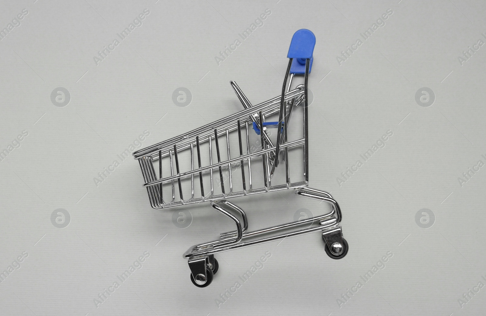 Photo of Small metal shopping cart on light grey background, top view