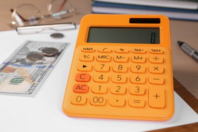 Photo of Orange calculator and money on table. Retirement concept