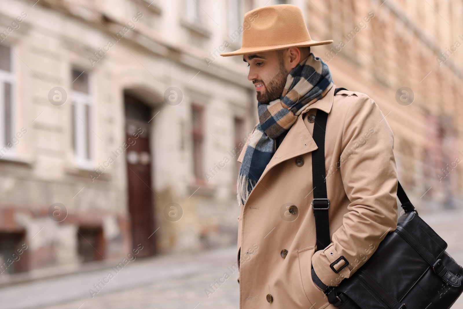 Photo of Handsome man in warm scarf on city street. Space for text