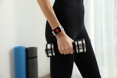 Young woman wearing smart watch during training indoors, closeup