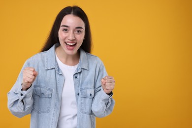 Photo of Portrait of happy surprised woman on orange background. Space for text