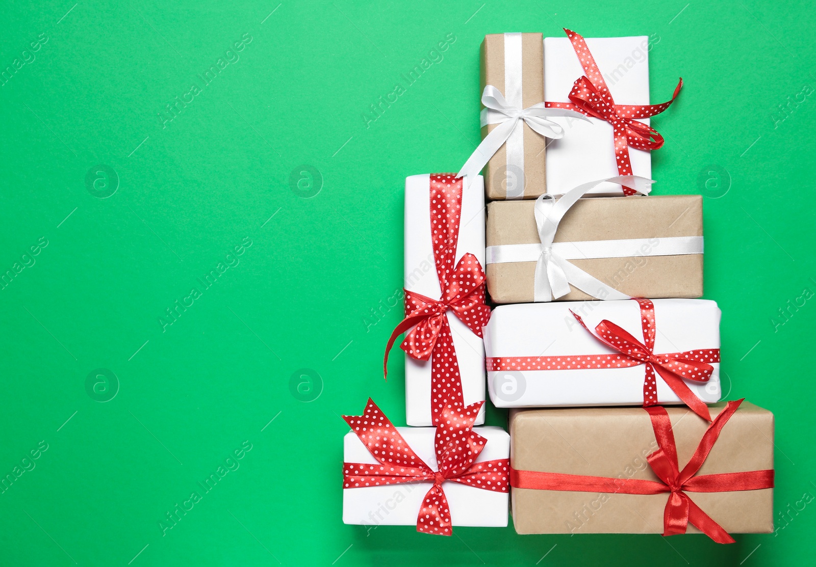 Photo of Christmas tree shape of gift boxes on green background, flat lay. Space for text