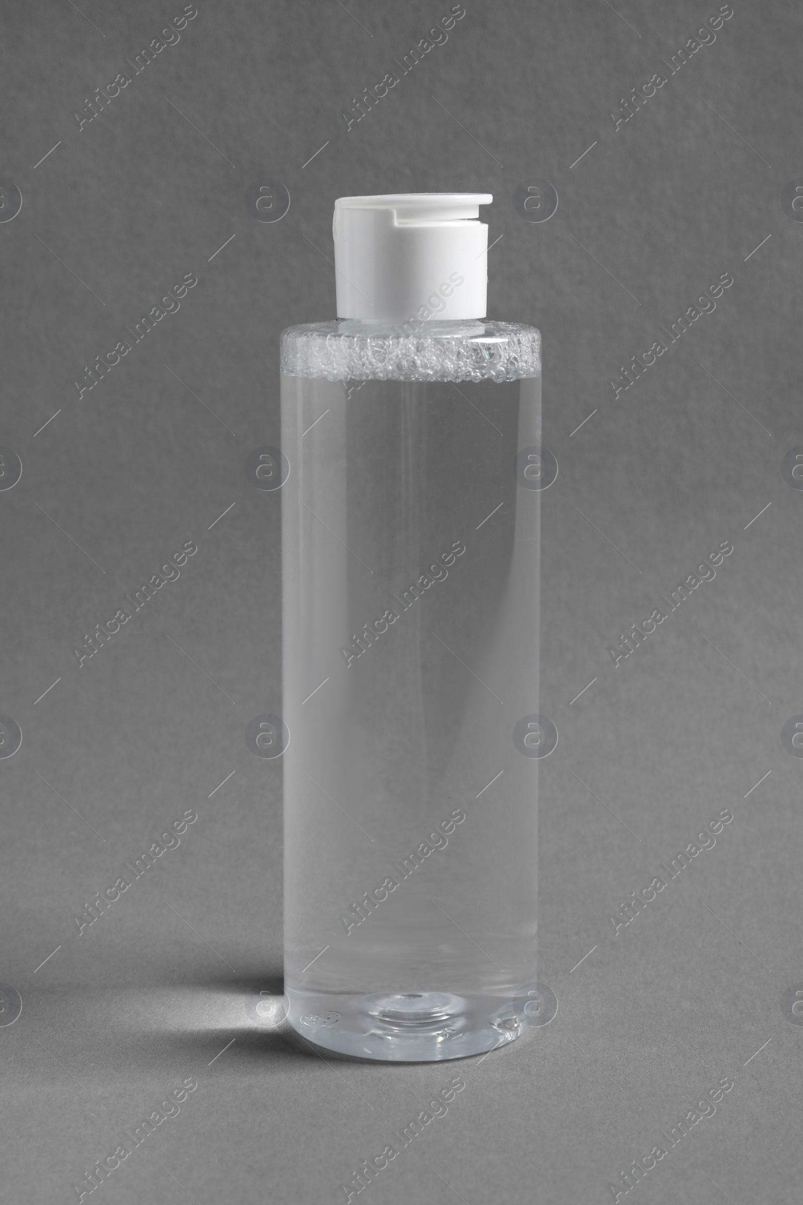 Photo of Transparent bottle with cosmetic product on grey background