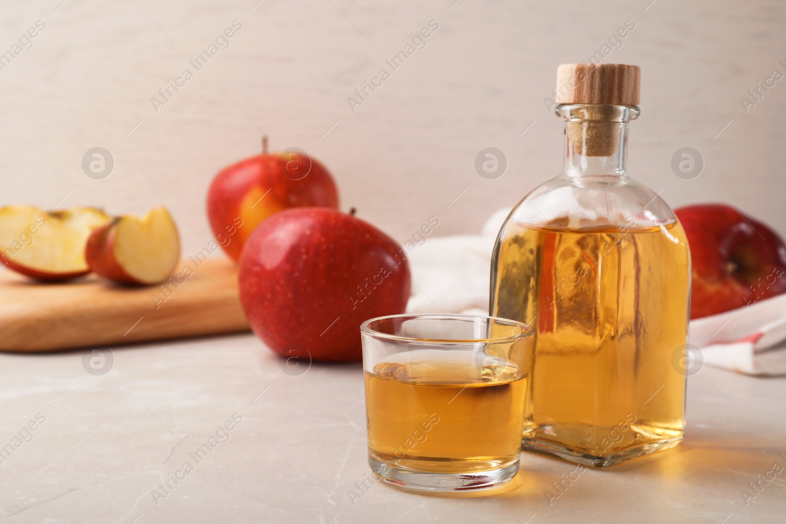 Photo of Composition with bottle and glass of apple vinegar on table. Space for text