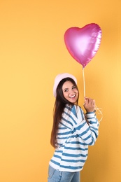 Photo of Portrait of young woman with heart shaped balloon on color background