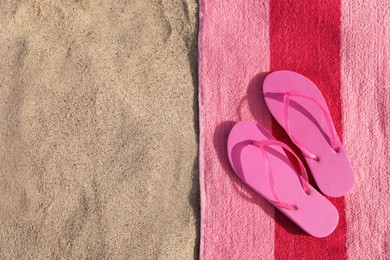 Photo of Beach towel and slippers on sand, flat lay. Space for text