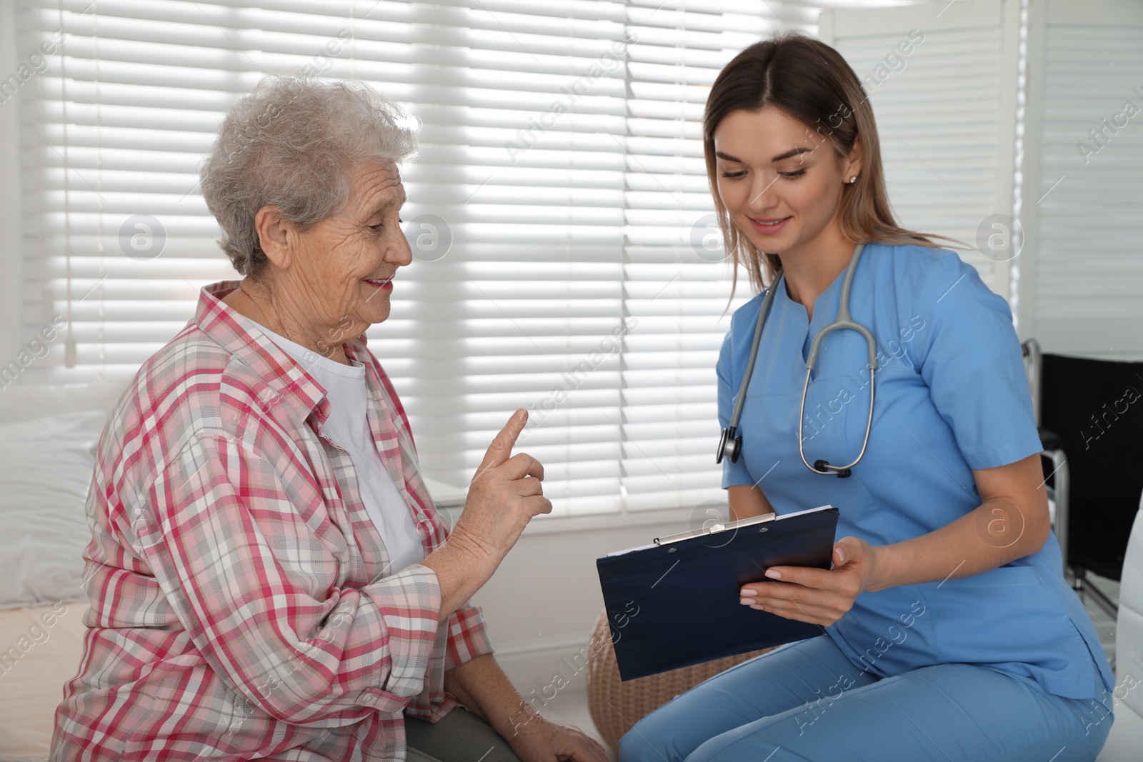 Photo of Young caregiver examining senior woman in room. Home health care service